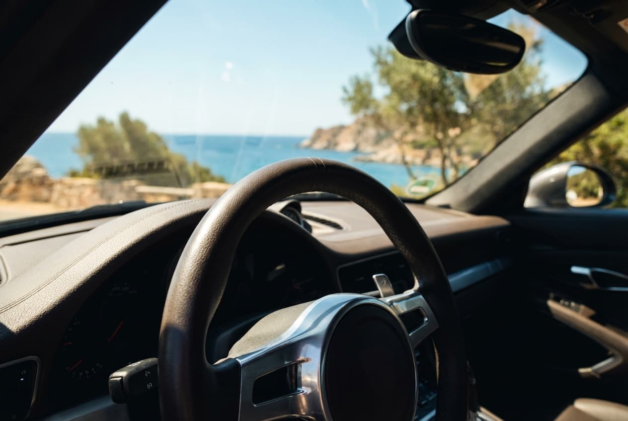 Les règles de conduite en sardaigne et l'état des routes Gros plan sur un volant de voiture avec un paysage sarde en arrière-plan flou